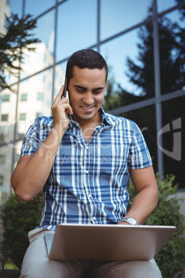 Executive using laptop while talking on mobile phone