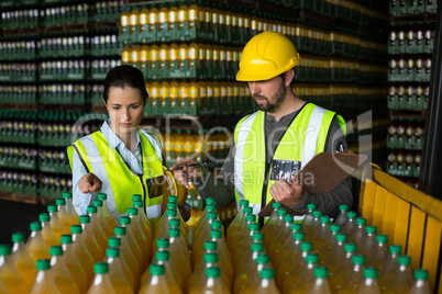 Two factory workers monitoring cold drink bottles