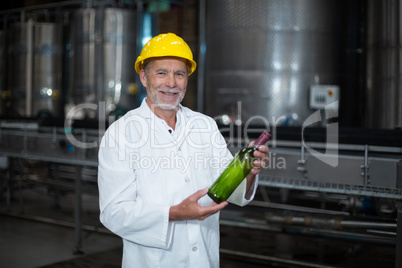 Factory worker examining a bottle in factory