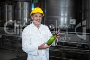 Factory worker examining a bottle in factory