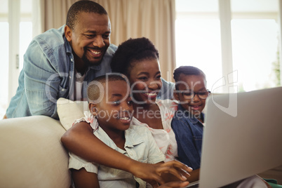 Parents and kids using laptop in living room