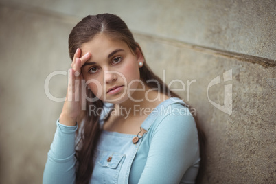 Anxious teenage girl leaning on wall