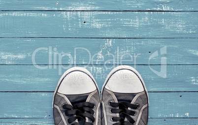 Blue men's old shabby sneakers on a blue wooden surface
