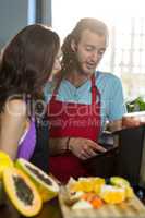 Shop assistants discussing with digital tablet at health grocery shop