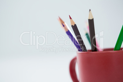 Colored pencils kept in mug on white background