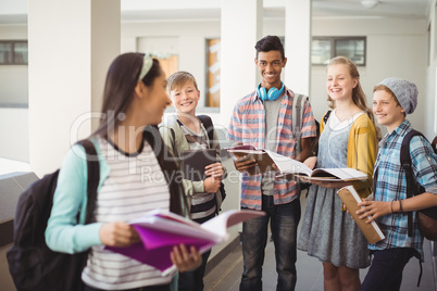 Group of smiling students standing with notebook in corridor