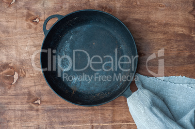 Black cast-iron empty frying pan on a brown wooden surface