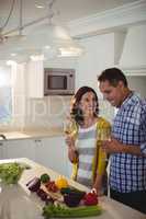 Couple holding glasses of wine in kitchen