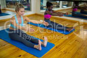 Two fit women doing stretching exercise on mat