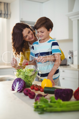 Mother and son mixing the salad in kitchen