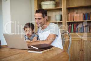 Father and son using laptop in study room