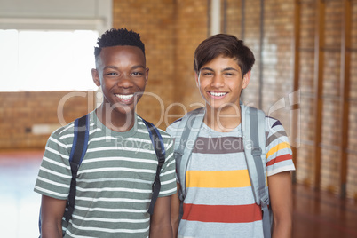 Portrait of happy schoolboys with schoolbag standing in campus