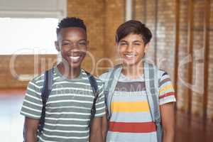 Portrait of happy schoolboys with schoolbag standing in campus