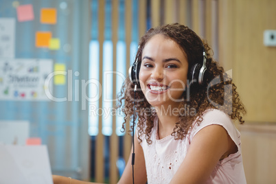 Portrait of female executive listening music on headphone