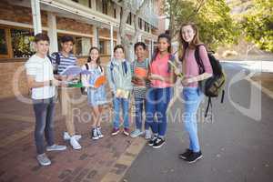 Portrait of happy students standing with books on road