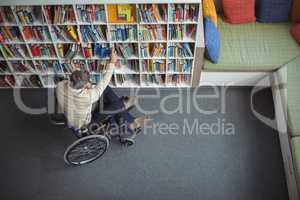Overhead view of disabled school teacher selecting book in library