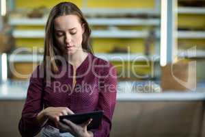 Female staff using digital tablet at counter