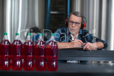 Male factory worker monitoring cold drink bottles