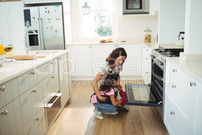 Mother and daughter checking the baked cookies in oven