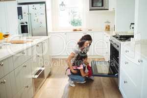 Mother and daughter checking the baked cookies in oven