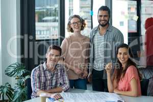 Portrait of smiling business executives with blueprint on table