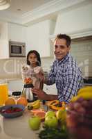 Portrait of father and daughter preparing smoothie in kitchen