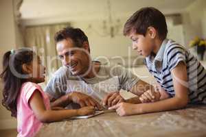 Father and kids using digital tablet in living room