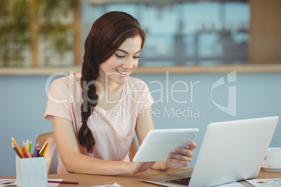 Beautiful business executive sitting at desk and using digital tablet