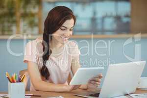 Beautiful business executive sitting at desk and using digital tablet