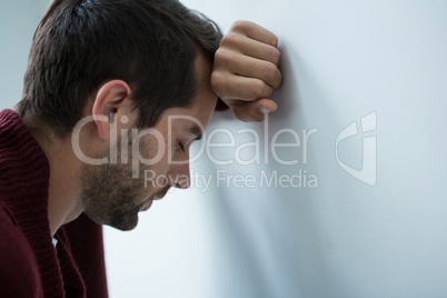 Stressed man leaning on wall