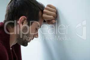 Stressed man leaning on wall