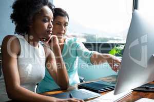 Female graphic designer pointing to desktop pc