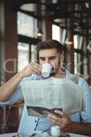 Executive reading newspaper while having coffee