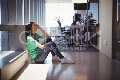 Worried female executive sitting in corridor