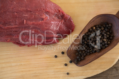 Beef steak and black pepper on wooden board