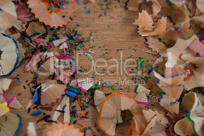 Colored pencils shavings on wooden background