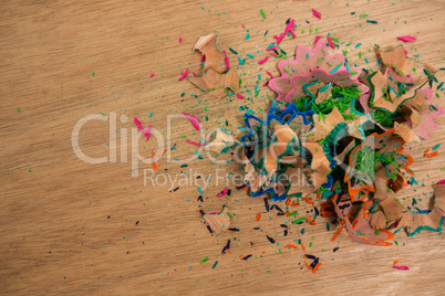 Colored pencil shavings on wooden background