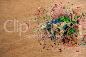 Colored pencil shavings on wooden background