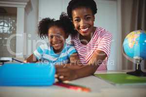 Portrait of mother assisting daughter with homework