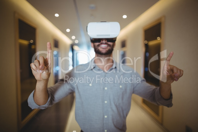 Male executive using virtual reality headset in corridor