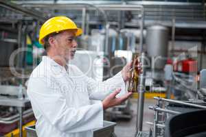 Factory worker examining a bottle in factory