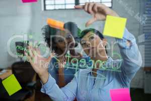 Female graphic designer pointing to the sticky notes on the glass