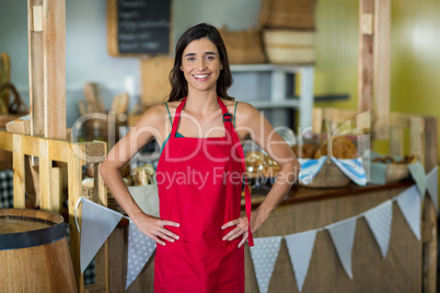 Portrait of female staff standing with hands on hip at counter