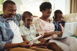 Parents and kids using laptop, smartphone and digital tablet on sofa