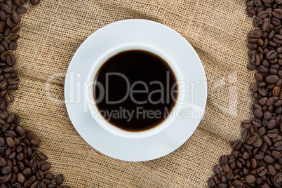 Coffee cup with coffee beans arranged on sack