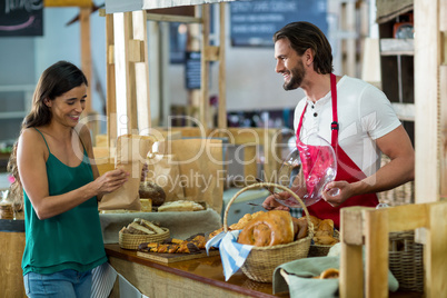 Smiling female customer receiving a parcel from bakery staff at counter