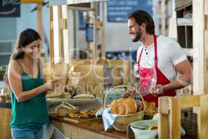 Smiling female customer receiving a parcel from bakery staff at counter