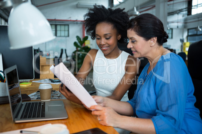 Female graphic designers discussing over a document