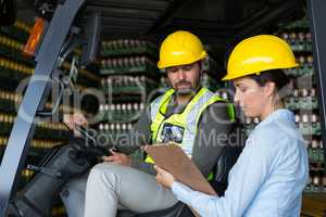 Factory workers checking record on clipboard in factory