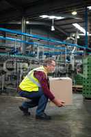 Factory worker carrying cardboard box in drinks production factory